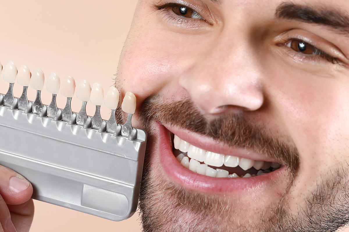 Patient comparing porcelain veneer shades for cosmetic dentistry treatment
